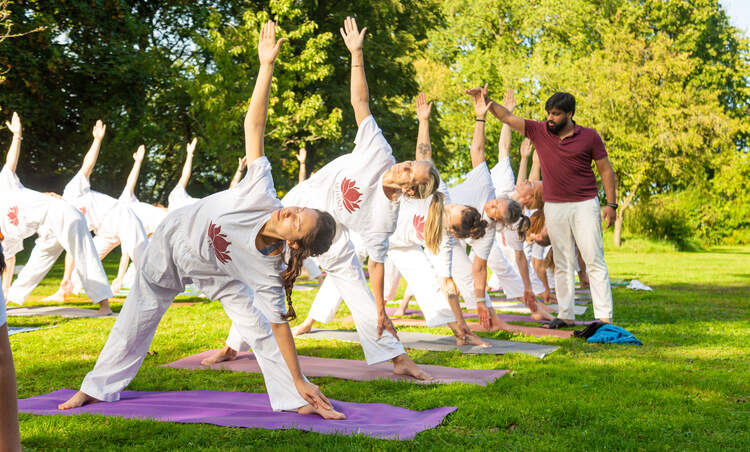 Een Indiase yoga-instructeur leert een klas studenten Hatha Yoga-houdingen buiten