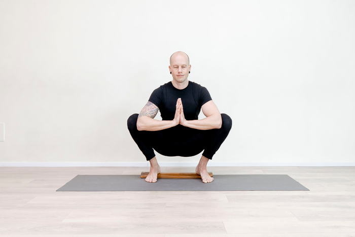 Mannelijke yogabeoefenaar in een yogahouding (Malasana).