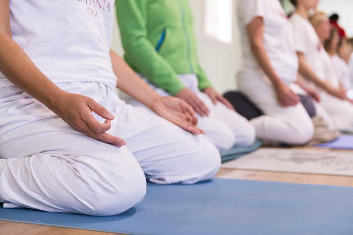 Yogabeoefenaars in een zittende meditatiehouding met een mudra-handpositie. Yogabeoefenaars in een zittende meditatiehouding met een mudra-handpositie.